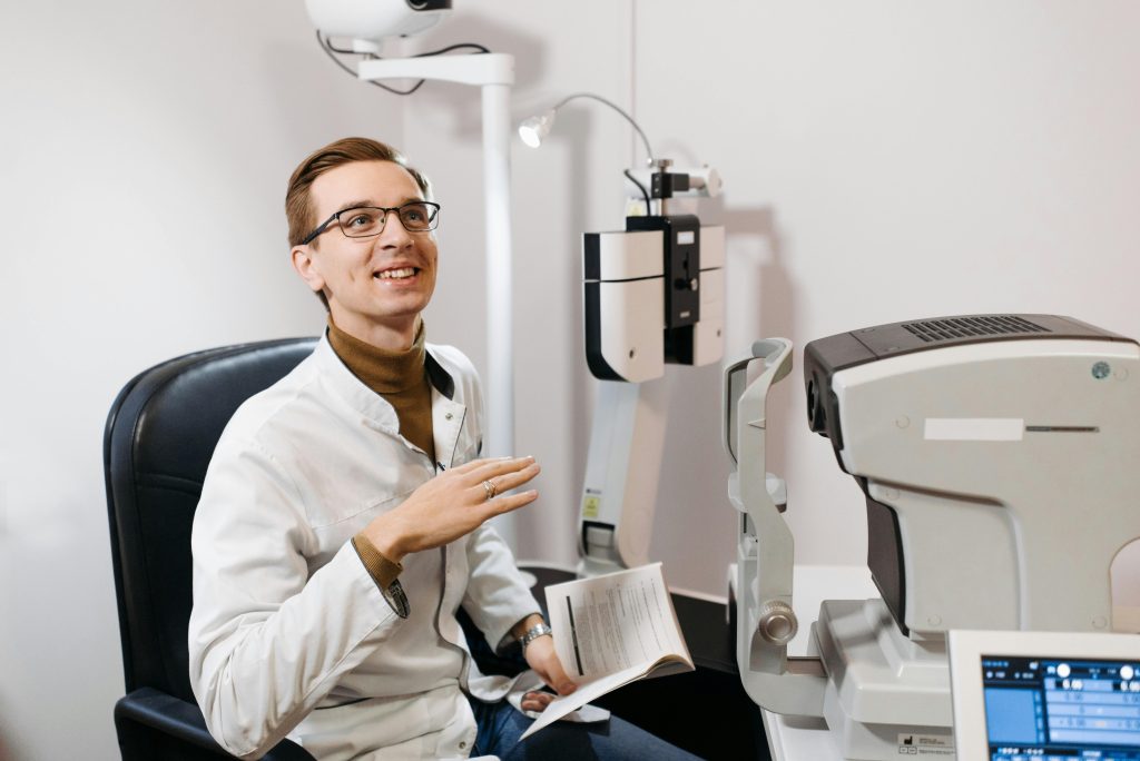 A professional optometrist smiles during an eye examination in a modern office setting.